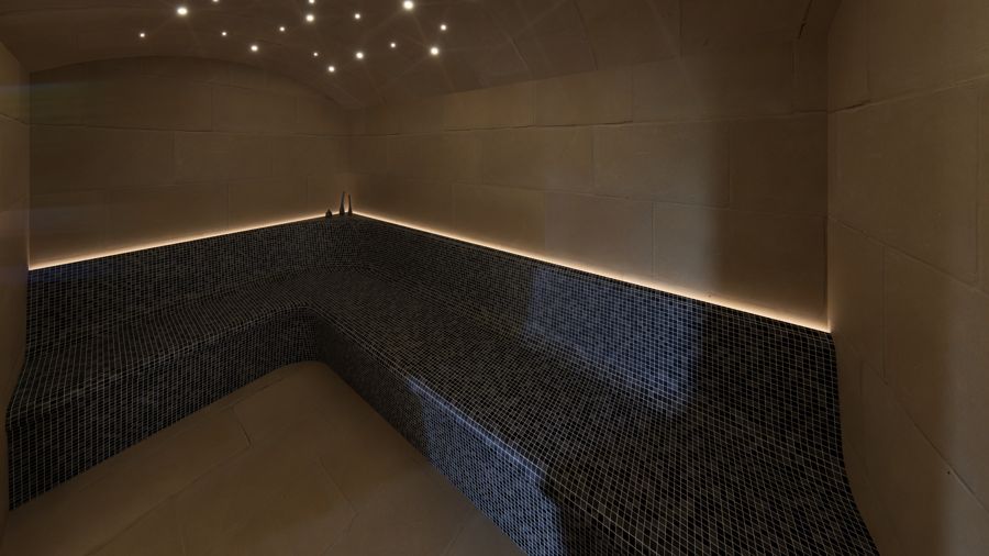 Zona de spa interior con banco de obra y luz indirecta.